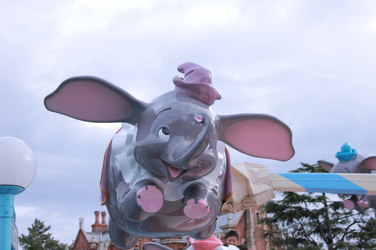 カラフルな帽子と洋服をまとったダンボが空を舞います