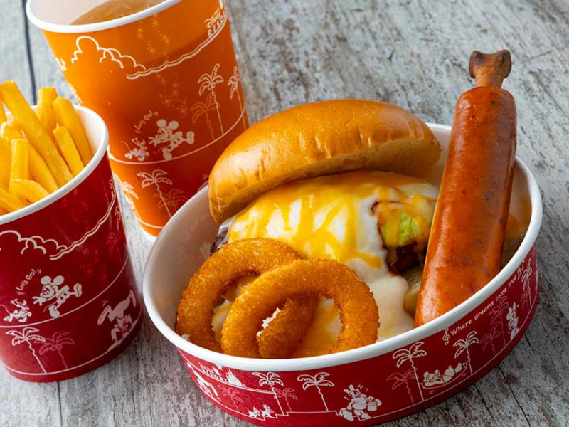 グラタン仕立てのアボカドチーズバーガー、骨付きソーセージとオニオンリング添え